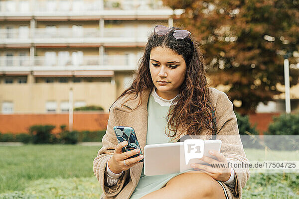 Curvy young freelancer with digital tablet working on smart phone