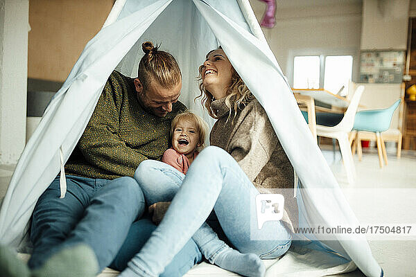 Playful family enjoying inside tent at home