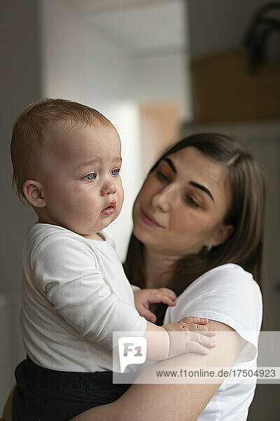 Mother looking at sad baby daughter at home