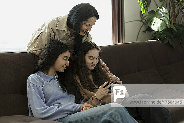Mother and daughters using mobile phone at home