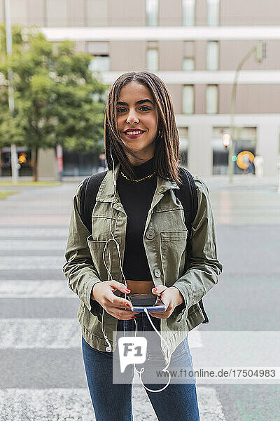 Young woman holding mobile phone on road