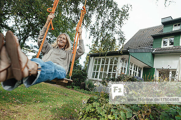 Playful woman swinging on swing at backyard