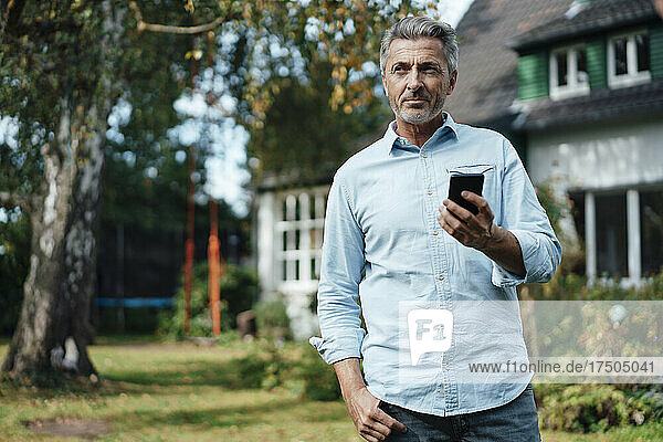 Mann hält Mobiltelefon im Hinterhof