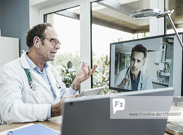 Doctor talking with colleague on video call through computer in clinic