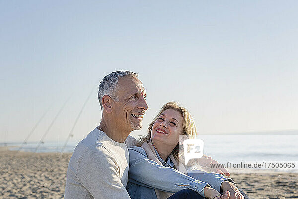 Lächelndes Paar sitzt am Strand