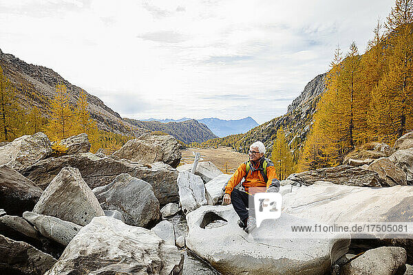 Senior hiker resting on rock at Rhaetian Alps  Italy