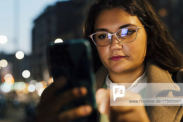 Junge Frau mit Brille und Mobiltelefon