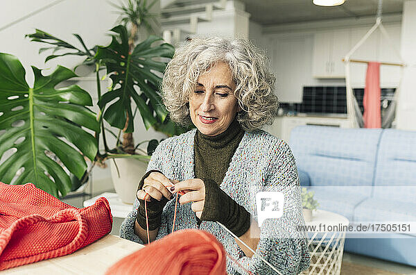 Senior woman knitting on table at home
