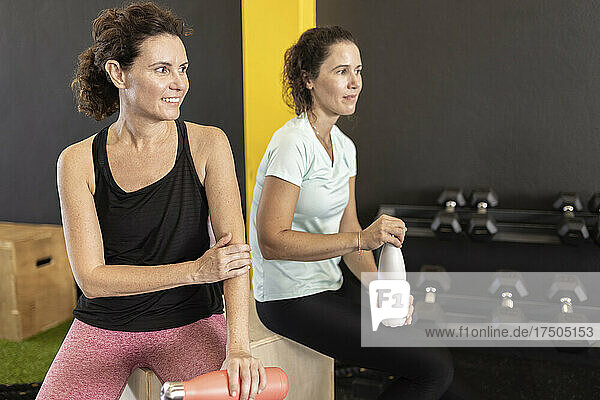 Sportswomen with water bottle sitting in gym