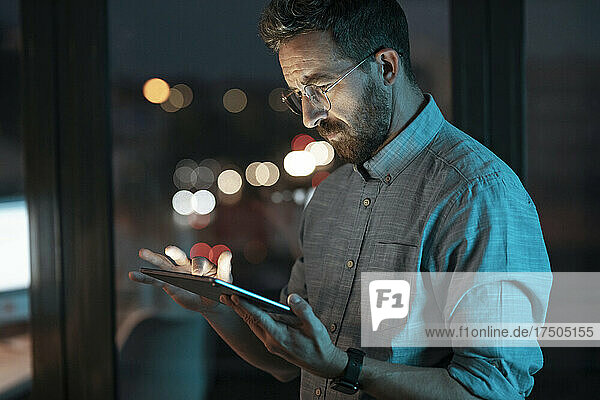 Businessman working on tablet PC at late night in office