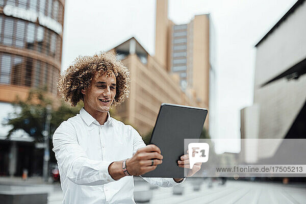 Smiling businessman using tablet PC on square