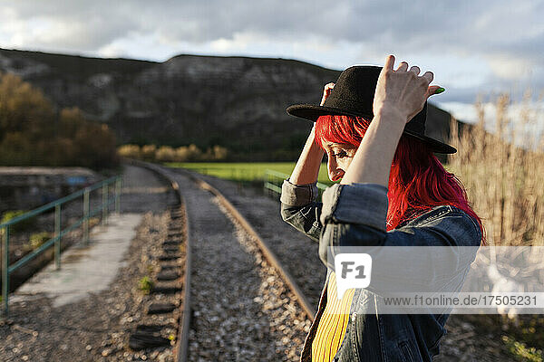 Woman wearing hat standing on railroad track