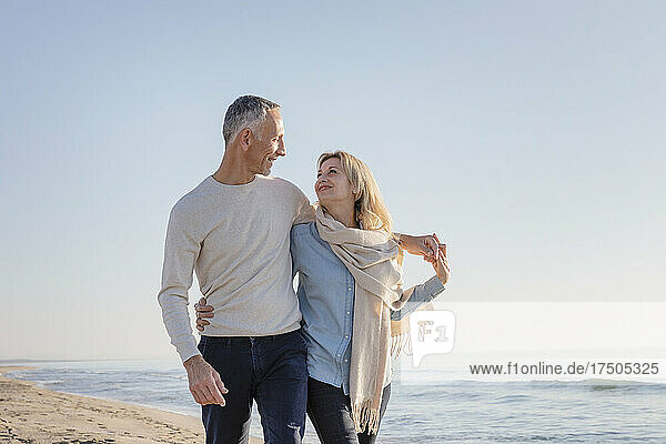 Woman with scarf looking at husband at beach