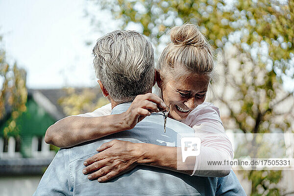 Woman holding key and hugging man at backyard