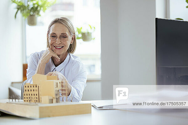 Smiling businesswoman checking model at workplace