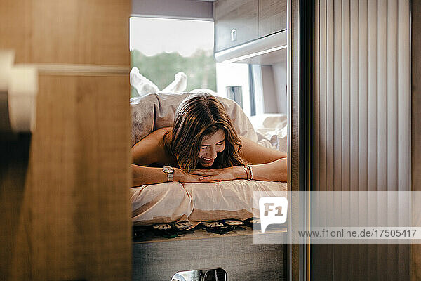 Fröhliche Frau entspannt sich im Wohnmobil auf dem Bett