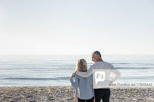 Mann schaut Frau an  die zusammen am Strand steht