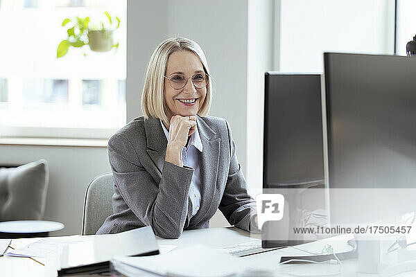 Senior businesswoman with hand on chin using computer in office