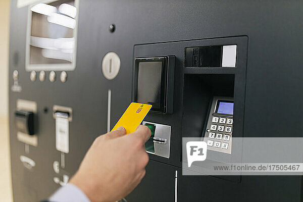 Geschäftsmann hält Kreditkarte am Geldautomaten
