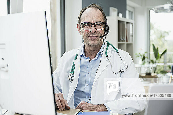 Smiling doctor in front of computer monitor at clinic