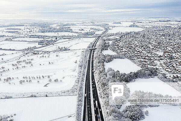 UK  England  Lichfield  Aerial view of multiple lane highway stretching along edge of snow-covered city