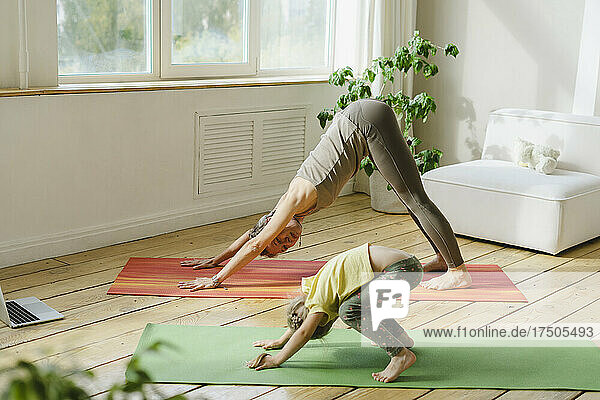 Girl practicing yoga pose with woman at home