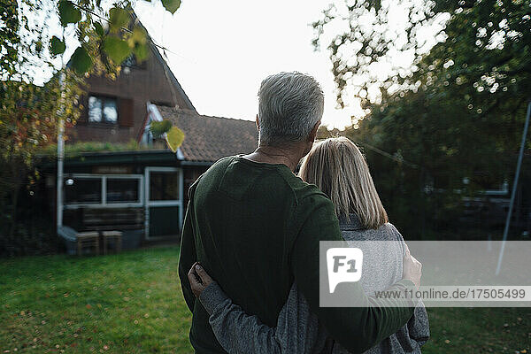 Couple standing with arms around at backyard