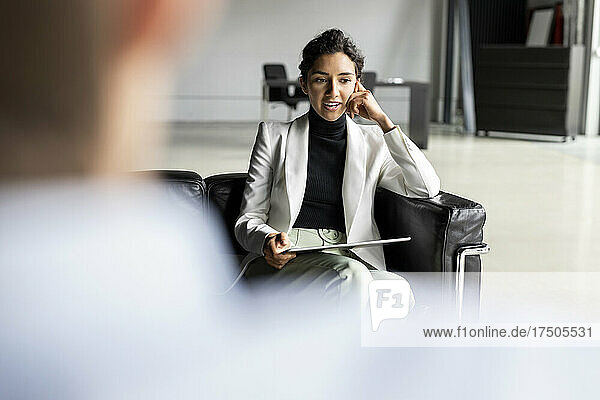 Thoughtful businesswoman with digital tablet discussing in lobby