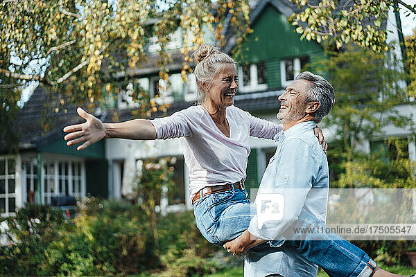 Cheerful man carrying woman at backyard