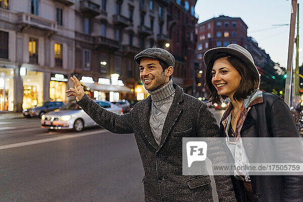 Glückliches junges Paar ruft in der Stadt ein Taxi