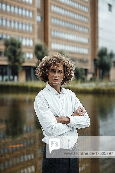 Businessman with arms crossed at riverbank