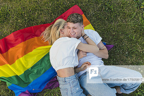 Young lesbian couple romancing on rainbow flag