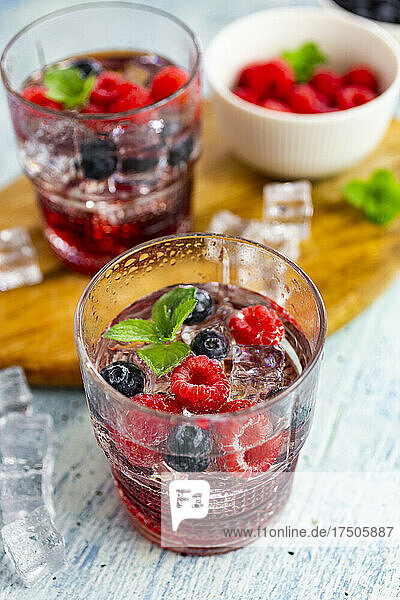 Two glasses of gin tonic with mint  ice cubes and raw berries