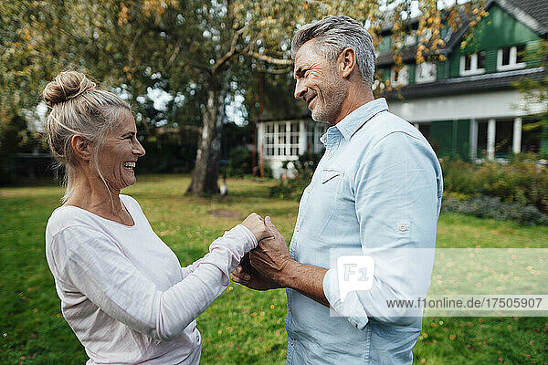 Cheerful couple holding each other's hands at backyard