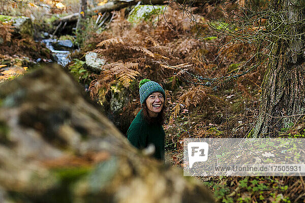 Smiling woman wearing knit hat in autumn forest