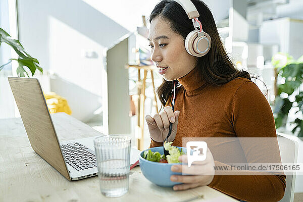 Businesswoman with laptop having lunch at table