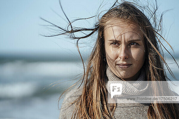 Young woman in turtleneck contemplating at beach