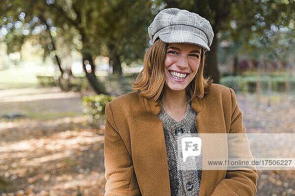Happy young woman wearing beret at autumn park