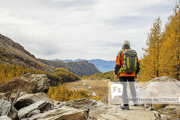Rucksacktourist steht auf einem Felsen in den Rätischen Alpen  Italien