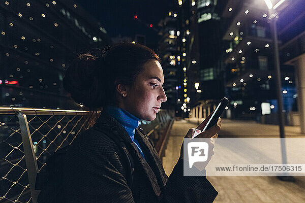 Working woman using smart phone at night in city