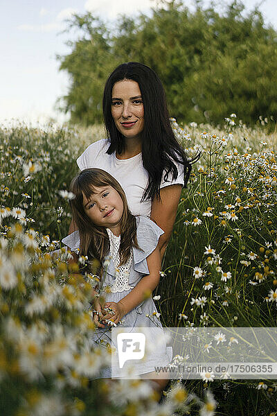 Mother and daughter standing amidst flowers in meadow