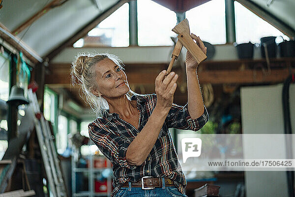 Woman holding wooden tool at garden shed