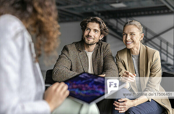 Happy businesswoman with businessman looking at colleague working on tablet pc