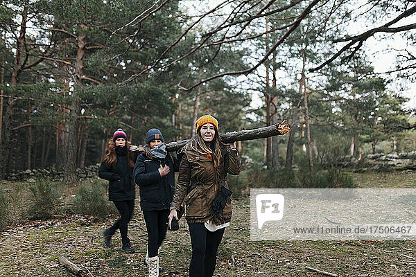 Friends carrying log on shoulders in forest