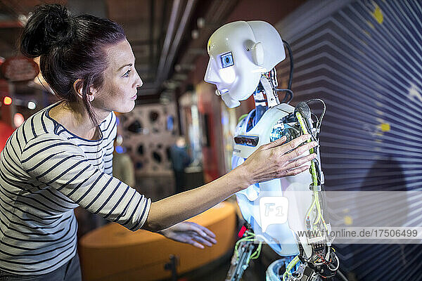 Technician gesturing near human robot in workshop