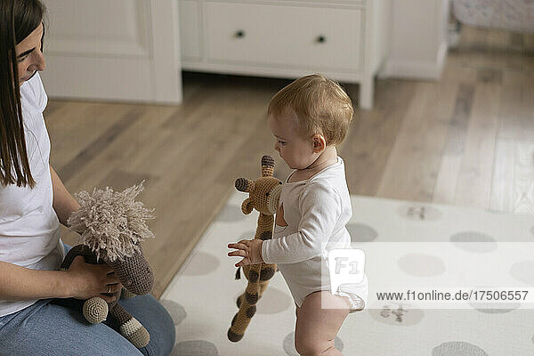 Baby girl and mother playing with stuffed toys at home