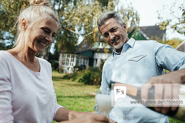 Smiling man pouring champagne in flute for woman at backyard