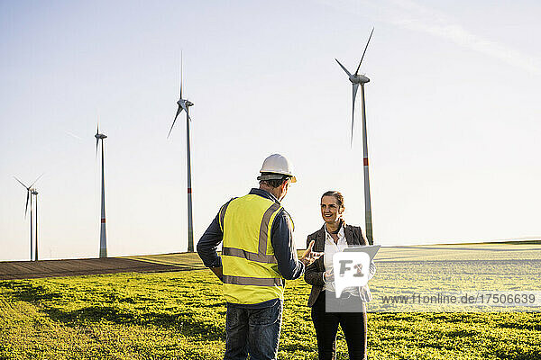 Engineer explaining to smiling colleague with digital tablet on sunny day