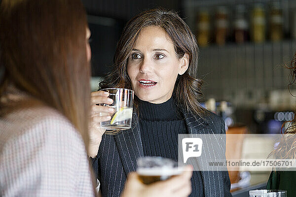 Businesswoman having discussion with colleagues in pub