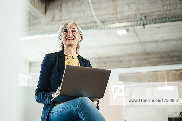 Glückliche Geschäftsfrau mit Laptop am Arbeitsplatz